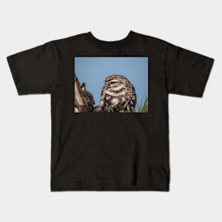 Little owl perched on at tree trunk Kids T-Shirt